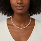 Woman wearing a pearl necklace against a neutral background