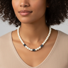 Woman wearing a pearl necklace with blue beads against a neutral background
