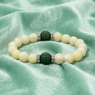 Pearl bracelet with green gemstone on a green fabric background