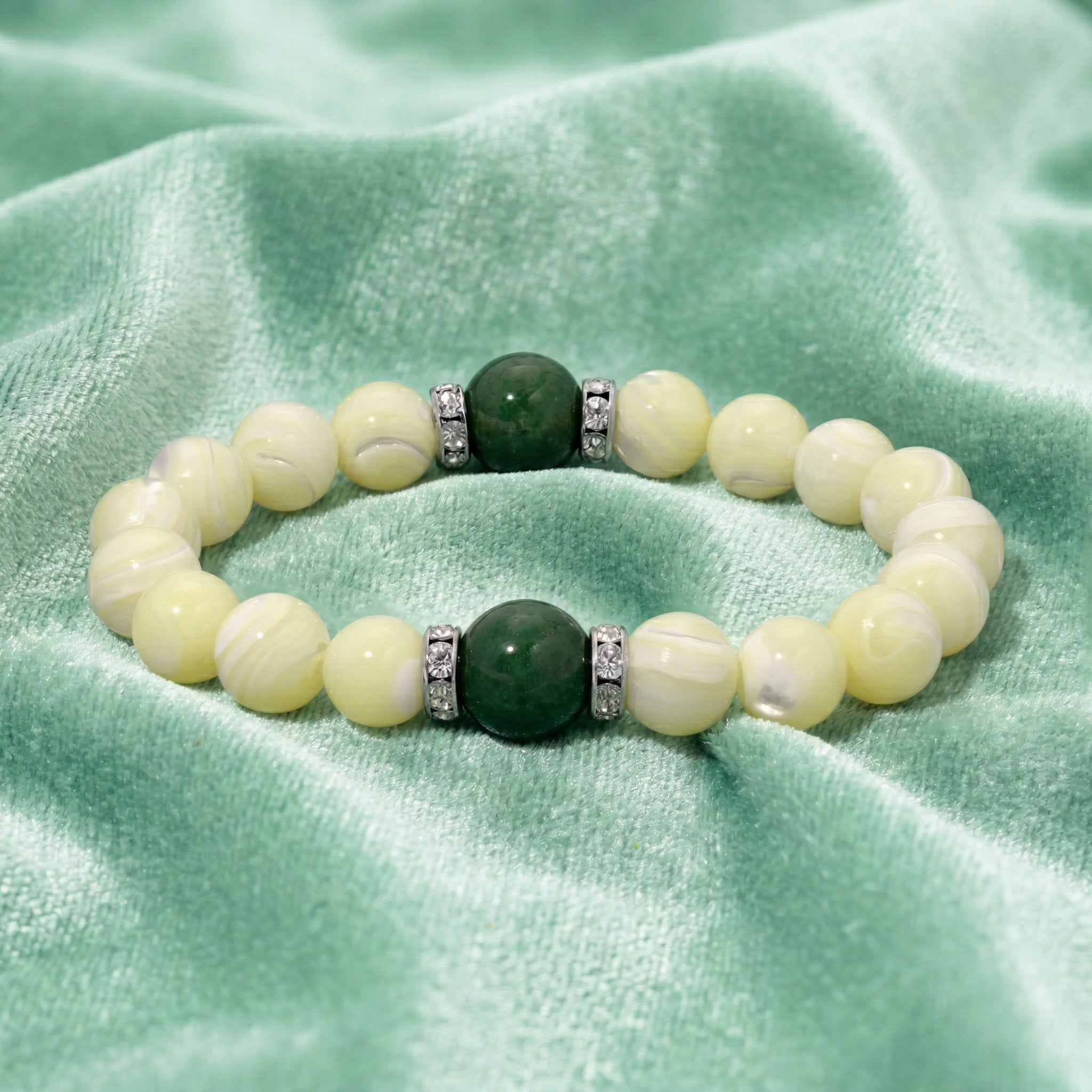 Pearl bracelet with green gemstone on a green fabric background