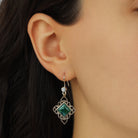 A close-up of a model's ear wearing Gold Filigree & Diamond Shaped Green Malachite Gemstone Drop Earrings