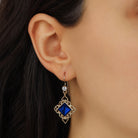Close up of a female model wearing Gold Filigree & Diamond Shaped Blue Crystal Drop Earrings