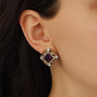 A close-up of a model's ear wearing a gold tone Royal Allure Square Amethyst & Crystal Stud Earrings