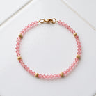Rose Pink European Glass Lantern Crystal & Gold Beaded Bracelet resting on white tile