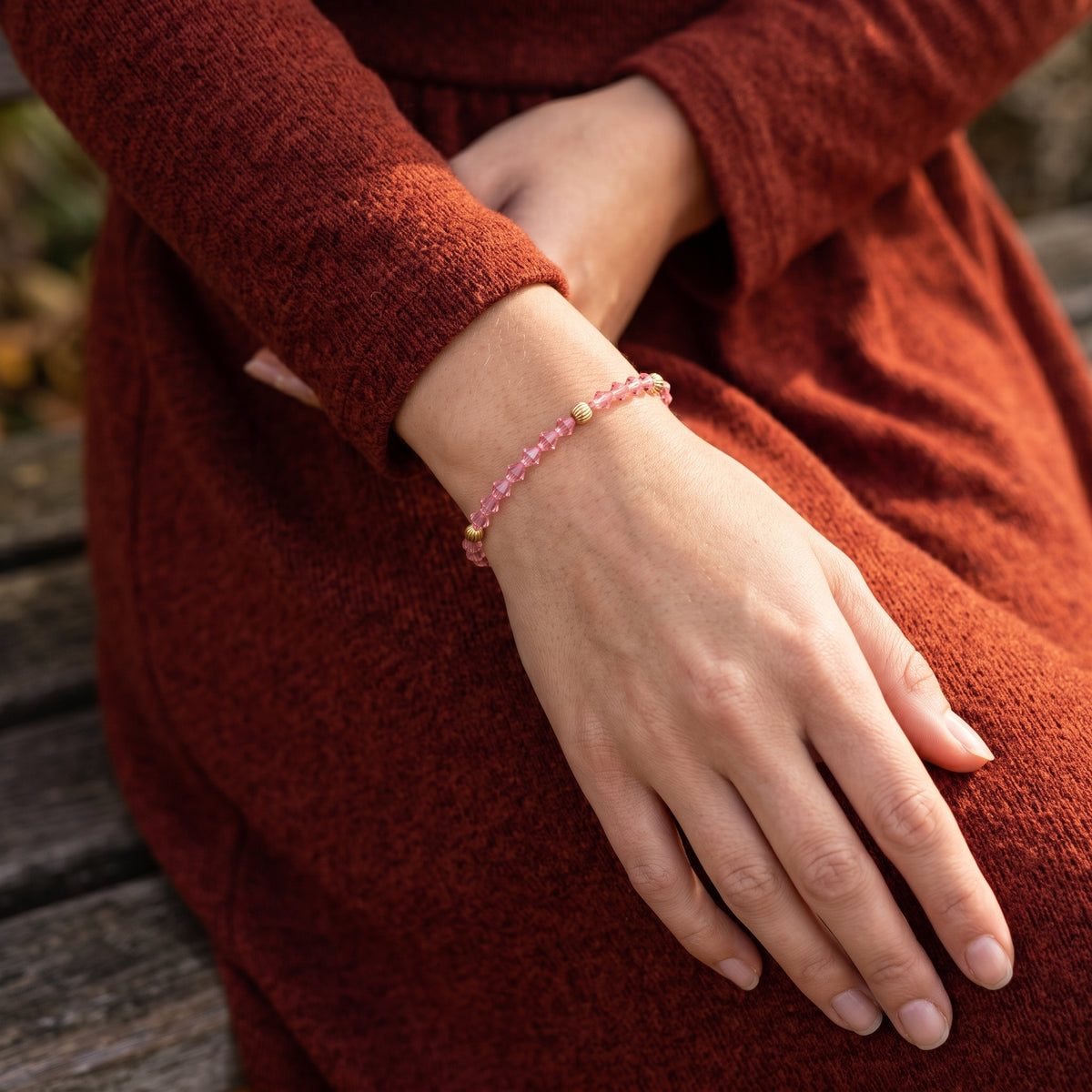 Woman in a fall outfit wearing a Rose Pink European Glass Lantern Crystal & Gold Beaded Bracelet on her wrist