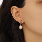 A close-up of a model's ear wearingGolden Pink Champagne Faux Pearl & Crystal Drop Stud Earrings