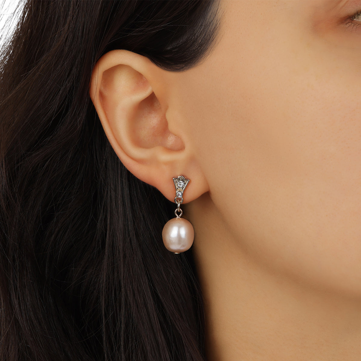 A close-up of a model's ear wearingGolden Pink Champagne Faux Pearl & Crystal Drop Stud Earrings
