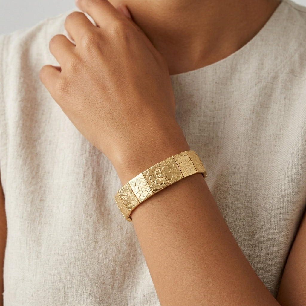 Gold floral bracelet on a wrist with a neutral background