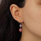 A close-up of a model's ear wearing a Round Coral Pink Dangling Bead & Baroque Rose Quartz Drop Earrings