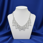 Silver necklace with Austrian Crystals on a mannequin bust against a blue satin background.