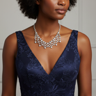 Woman wearing a deep neckline navy dress with a silver necklace that has Austrian Crystals against a neutral background.