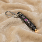 Pink crystal stone accented flashlight keychain resting on beige fabric