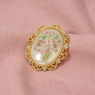 Golden Oval Faux Pearl Stone Floral Decal Pin resting on pink linen fabric 