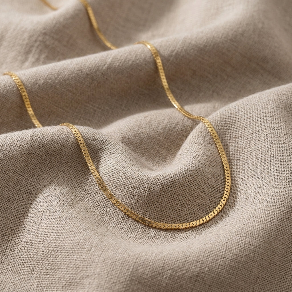 Gold chain necklace on a textured beige fabric background
