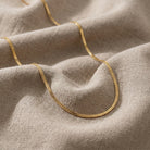Gold chain necklace on a textured beige fabric background