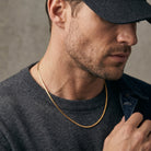 Man wearing a gold chain necklace with a neutral background