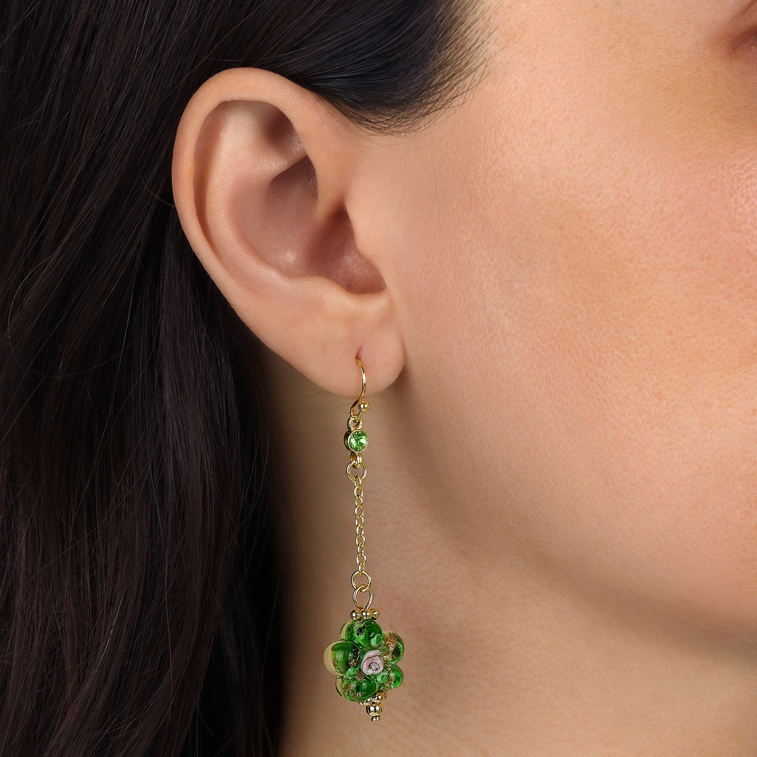 A close-up of a model's ear wearing a Green Blooming Flower Bead & Crystal Dangle Earrings