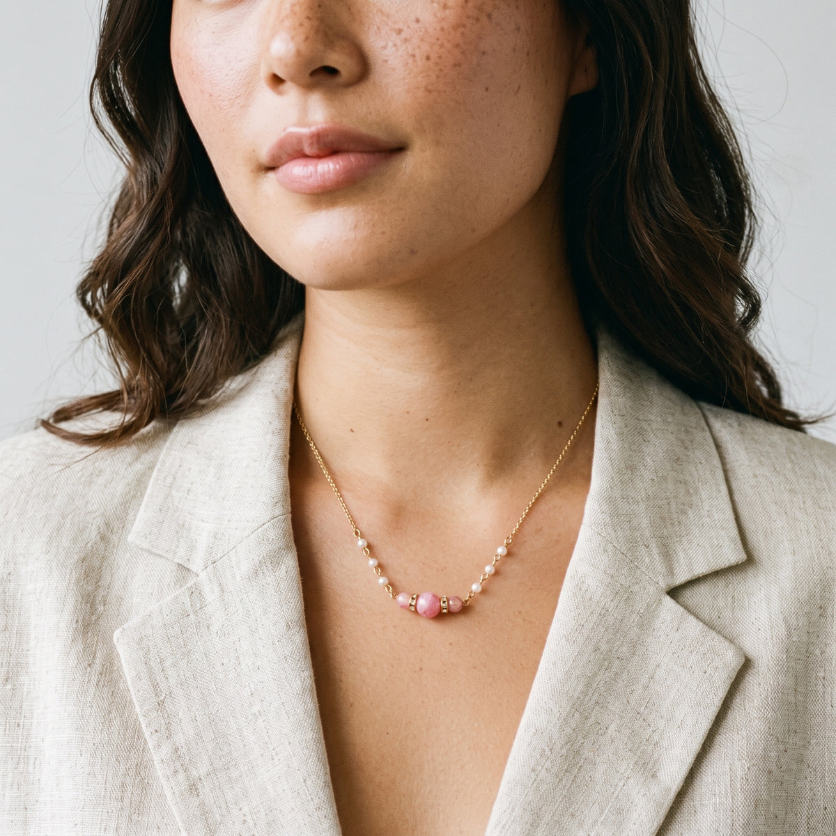 A close-up of a woman wearing a delicate Pink Peppermint Beaded & Faux Pearl Chain Necklace 15" + 3" Extension styled with a light beige blazer.