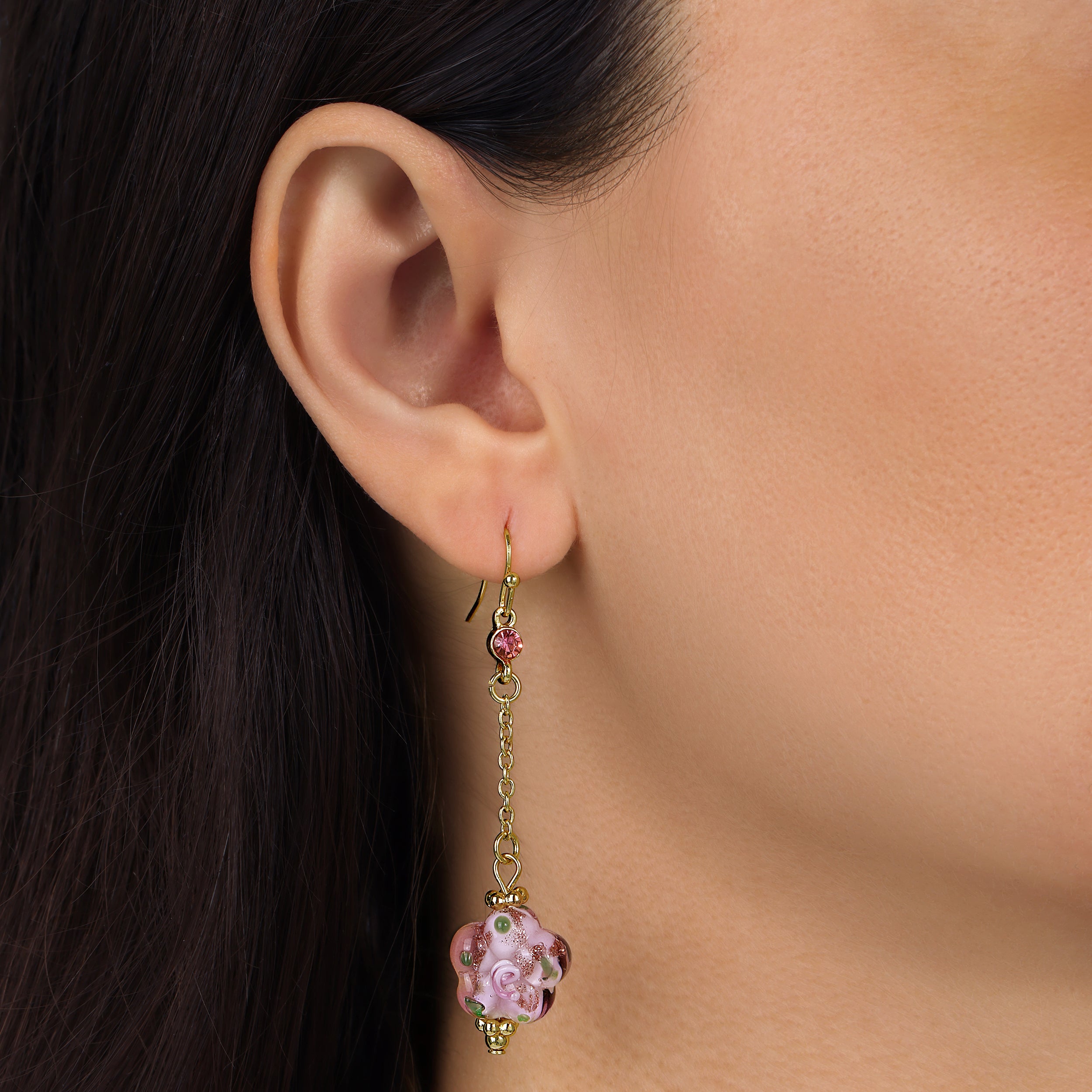 A close-up of a model's ear wearing a Pink Blooming Flower Bead & Crystal Dangle Earrings