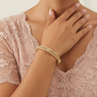 Gold bracelet on a person wearing a lace dress
