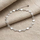 Silver anklet on a textured beige fabric background