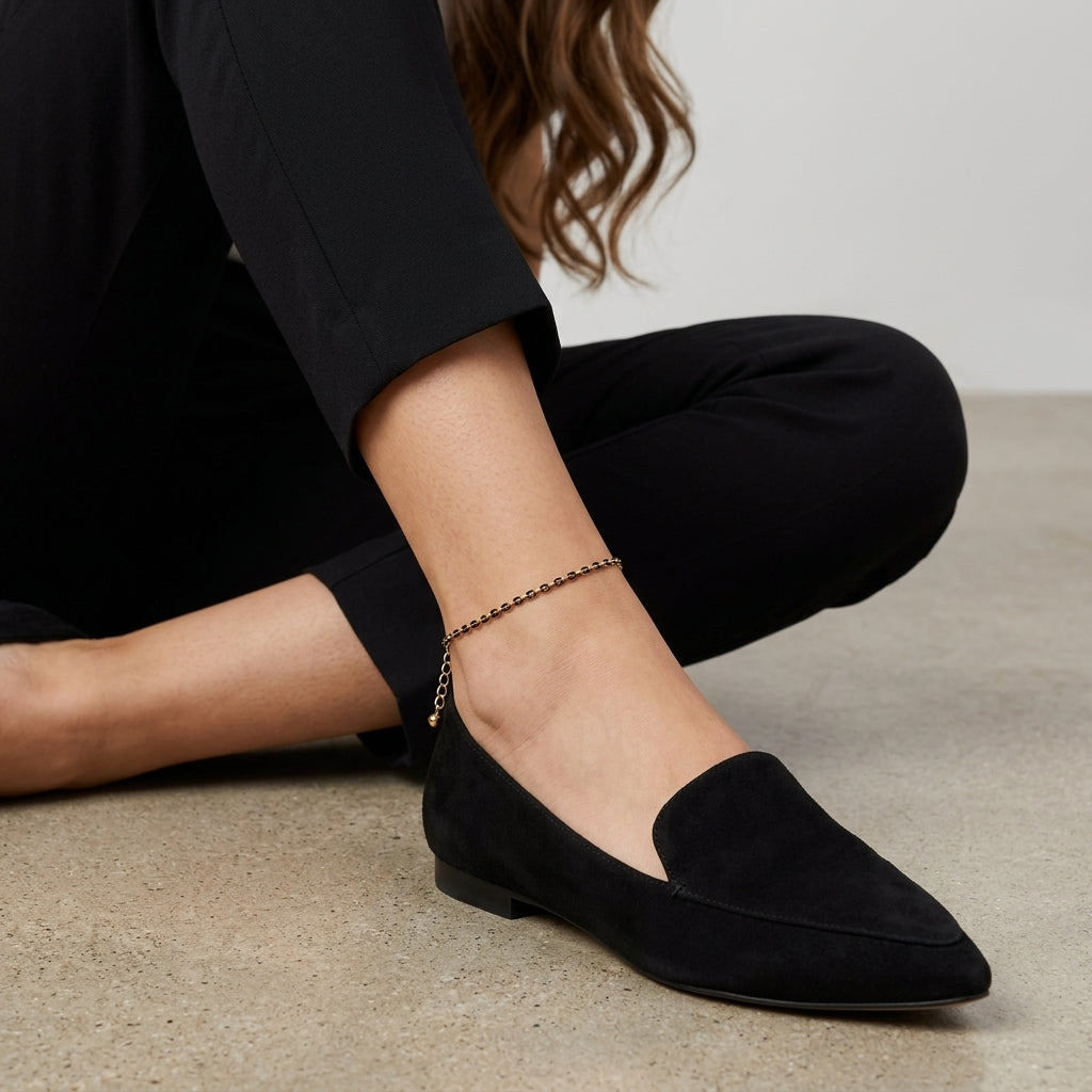 Woman in black pants and black loafers wearing a gold and black tone anklet
