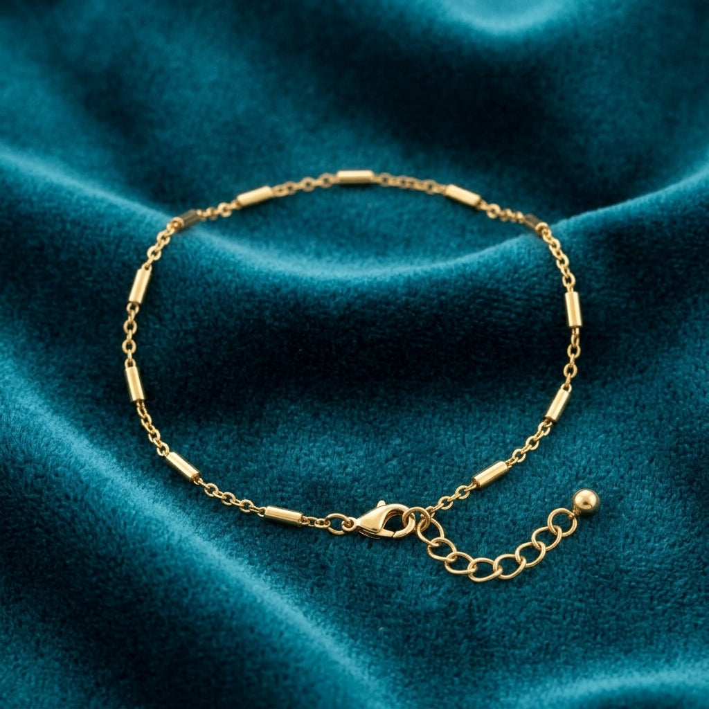 Gold tone anklet resting on turquoise fabric