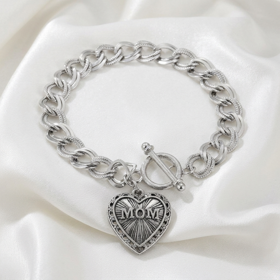 Silver chain bracelet with a heart-shaped 'MOM' charm on a white fabric background