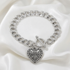 Silver chain bracelet with a heart-shaped 'MOM' charm on a white fabric background