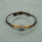 Black Diamond Fireball Crystal Brown Leather Cord Linen Wrapped Bracelet set against a textured gray-green background.