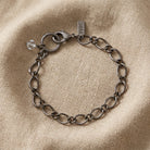 Pewter chain bracelet with a clear crystal stone bead on beige linen fabric