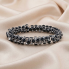 Silver bracelet with black beads on a beige fabric background