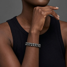 Person wearing a silver bracelet with black beads on a dark background