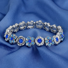 Silver floral bracelet with blue crystals on a blue fabric background