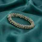 Bracelet with green crystals on a teal fabric background