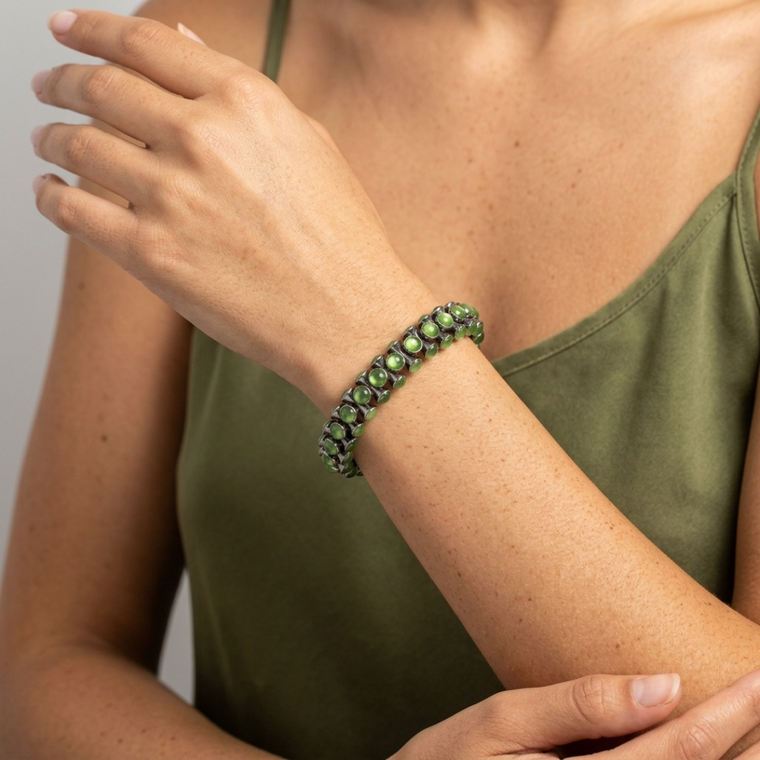 Person wearing a green crystal on a plain background