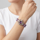 Person wearing a bracelet with purple beads on a plain background