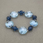 Montana Blue & Light Sapphire Blue Faceted Stone Stretch Bracelet displayed on a textured gray stone background.