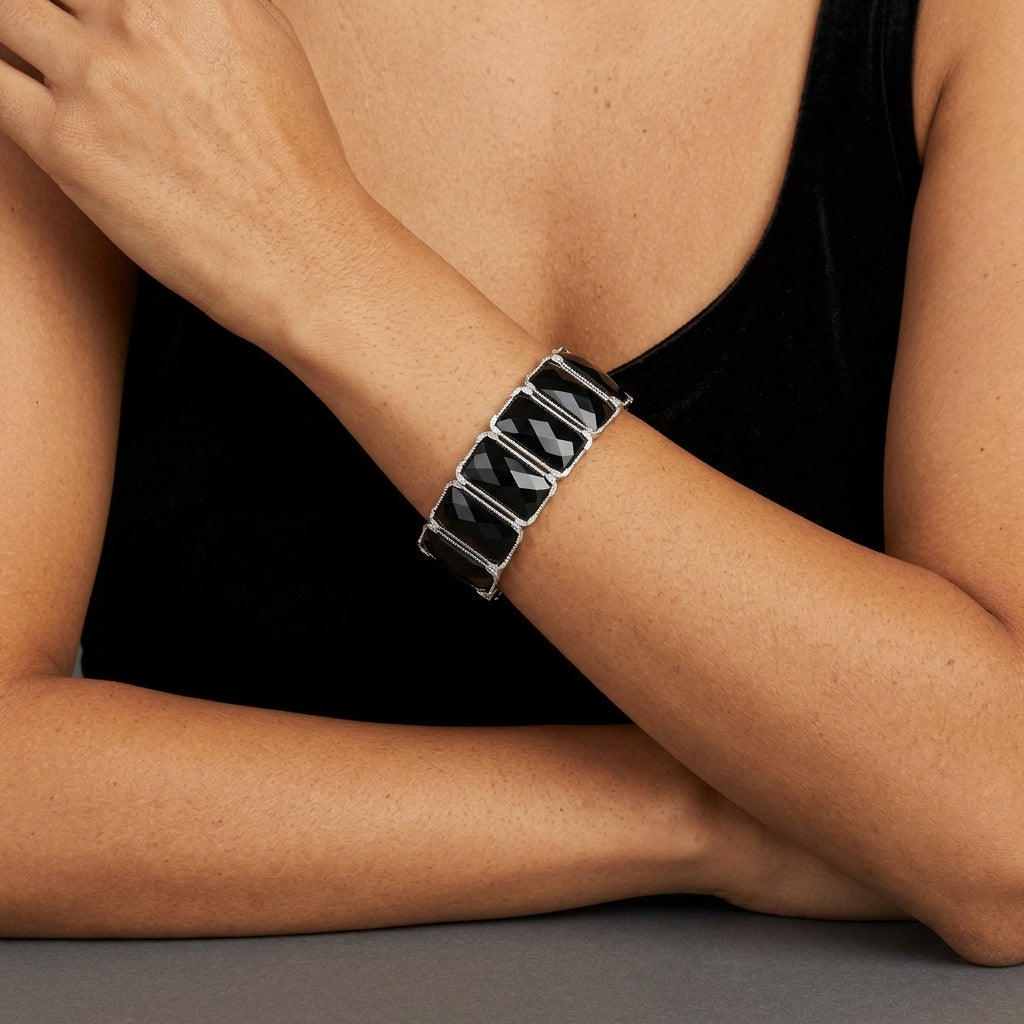 Woman in a black dress wearing a black stone bracelet with silver tone accents