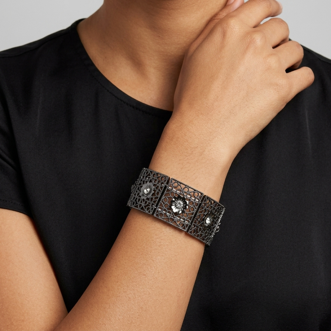 Person wearing a black laced stretch bracelet with crystals on a plain background