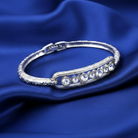 Silver bracelet with crystals on a blue satin background