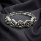 Silver bracelet with rose designs on a dark fabric background