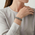 Person wearing a silver bracelet with floral design on a neutral background