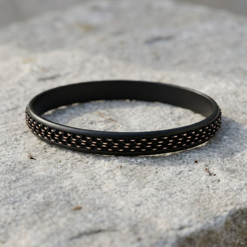 Black and gold bracelet with textured pattern on a stone surface