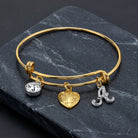 Gold Heart Initial Crystal Charm Bangle Bracelet resting on dark marble surface
