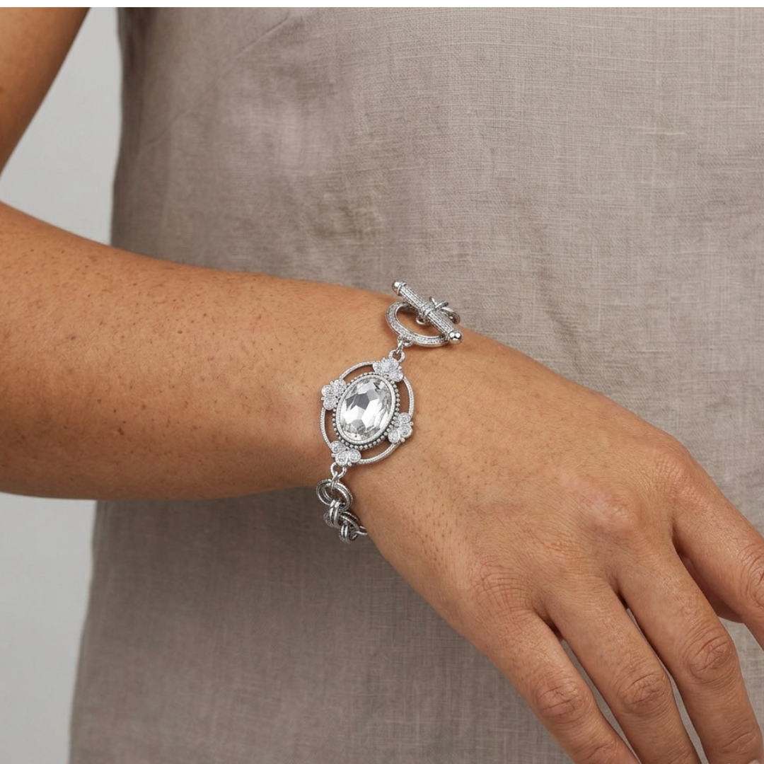 Silver bracelet with a large clear crystal on a wrist against a neutral background