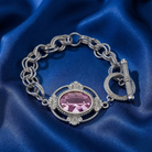 Silver bracelet with a pink crystal on blue satin fabric