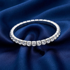 Silver bracelet with clear crystals on a blue fabric background
