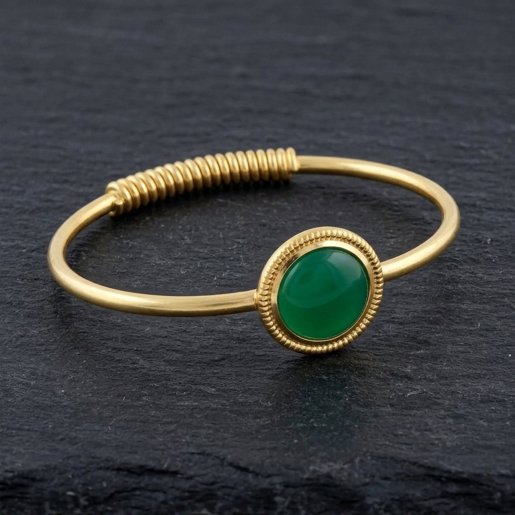 Gemstone Golden Spring Hinge Bracelet with a Jade gemstone on a dark stone surface