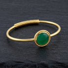 Gemstone Golden Spring Hinge Bracelet with a Jade gemstone on a dark stone surface